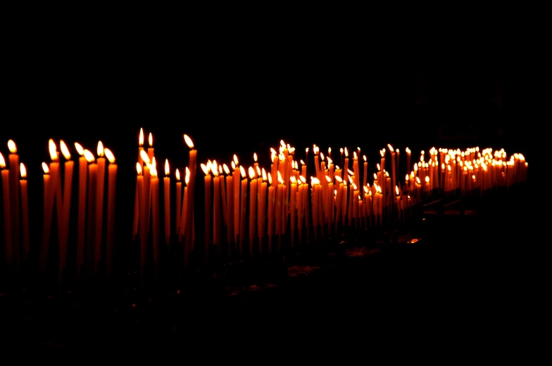 rows of candles lit against the dark background