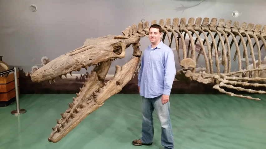 a man standing next to a fossil model of a dinosaur