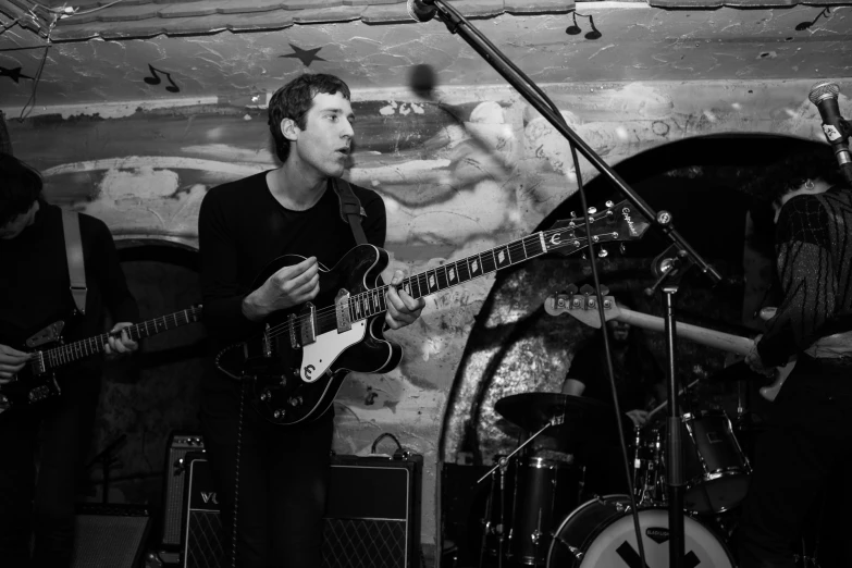 a man playing an electric guitar next to a drum