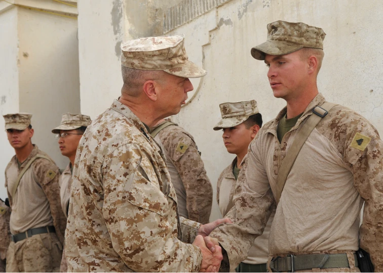 the men are shaking hands together in uniform