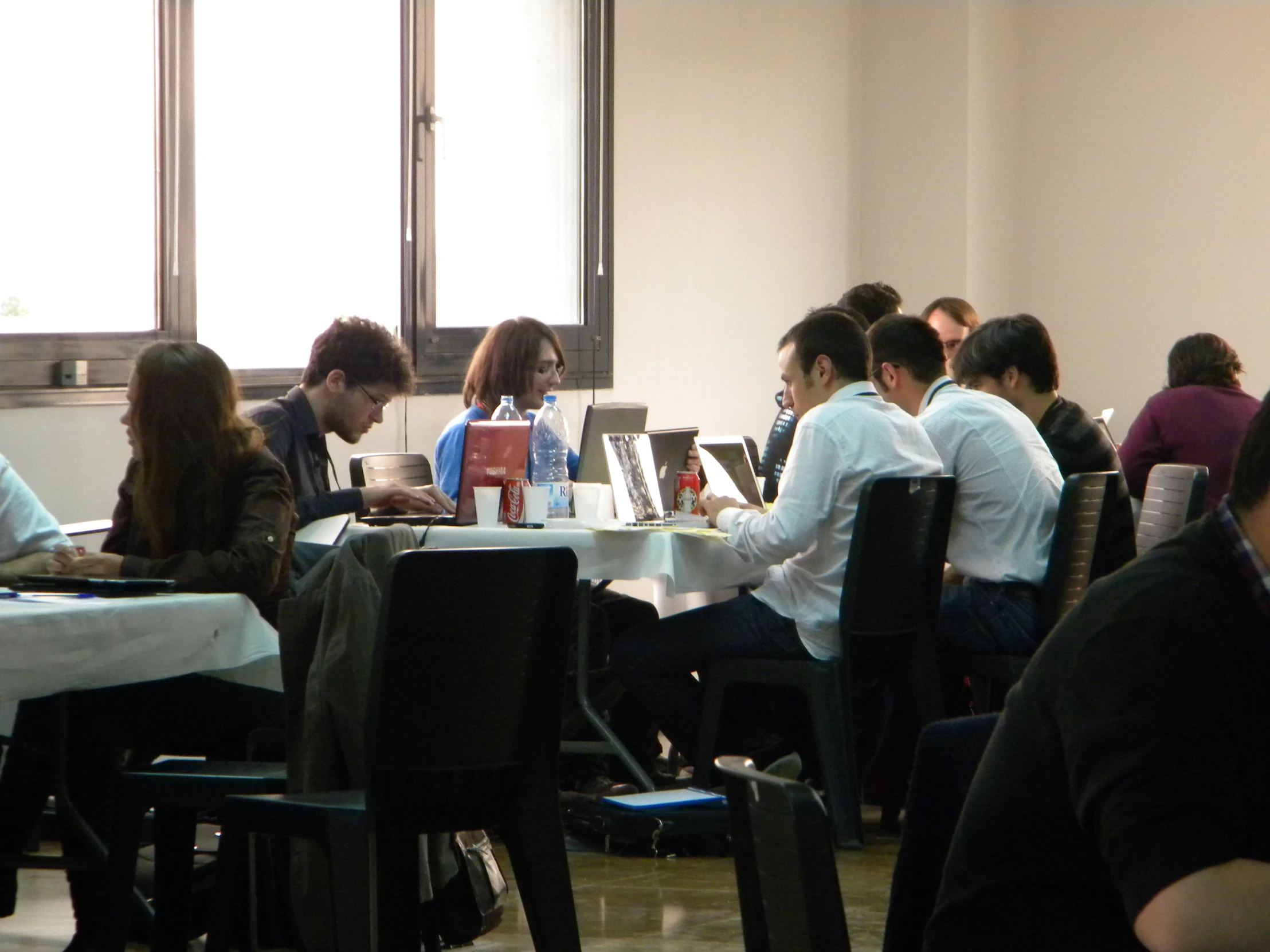 a group of people sitting at tables typing on laptops