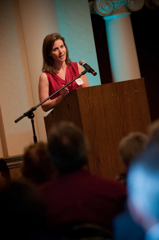 woman speaking in front of large audience at event