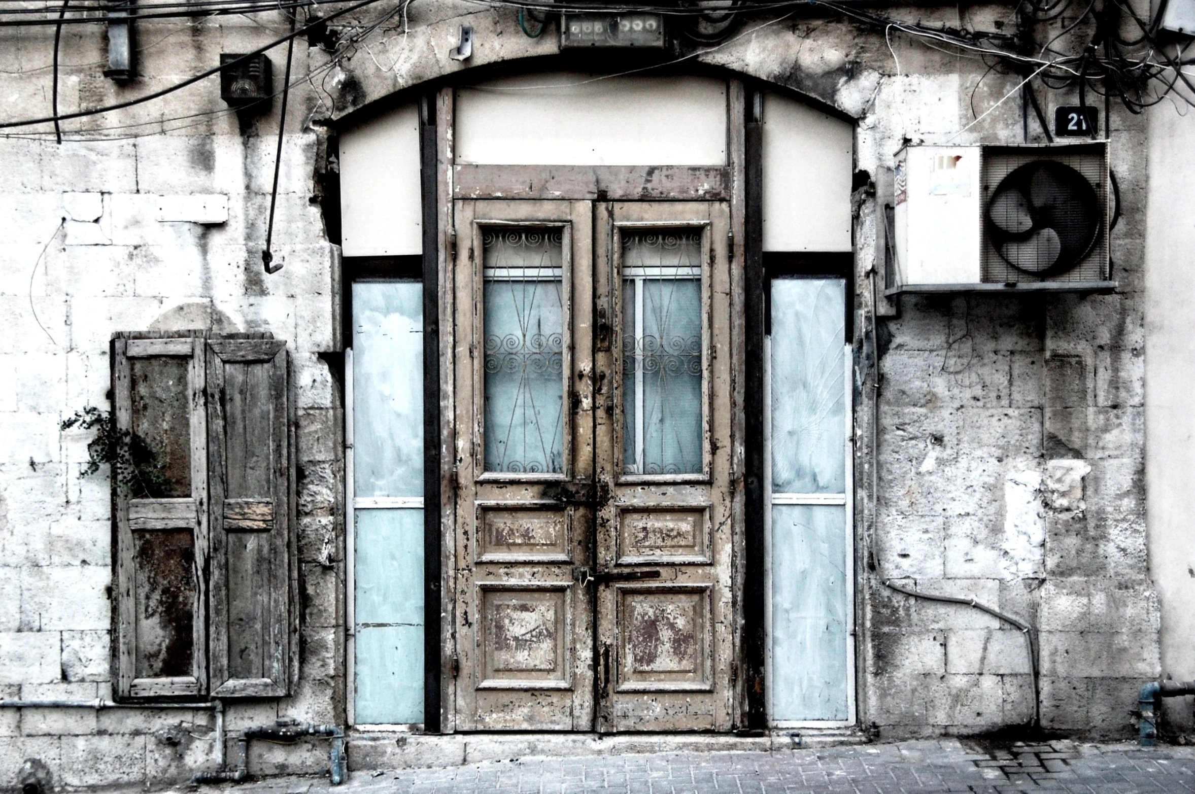 a large, dirty building with broken glass and an old door