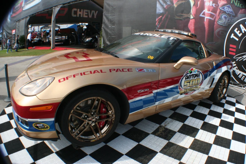 a very shiny gold race car sitting on top of a checkered floor