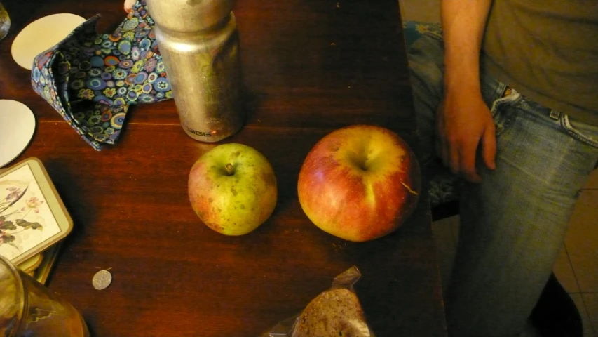 apples are laid out on a table with an older style coffee can and a paper towel