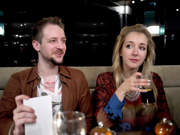 two people sitting at a table holding wine glasses