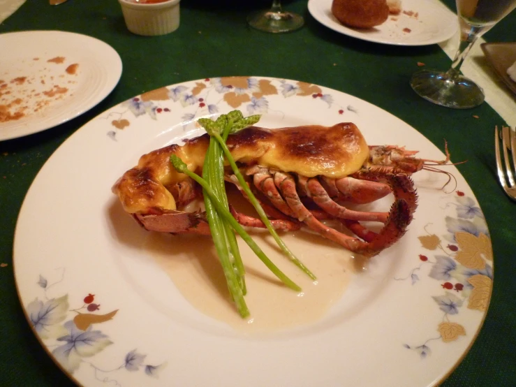 lobster in a white and blue dish and green asparagus on the plate