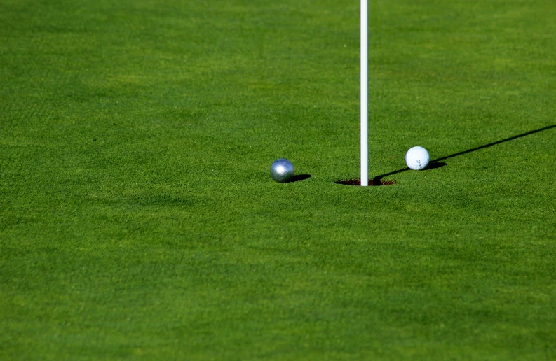 two golf balls on a green with an arrow pointing to one