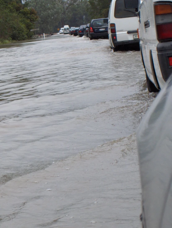 water running over cars near a street and grass