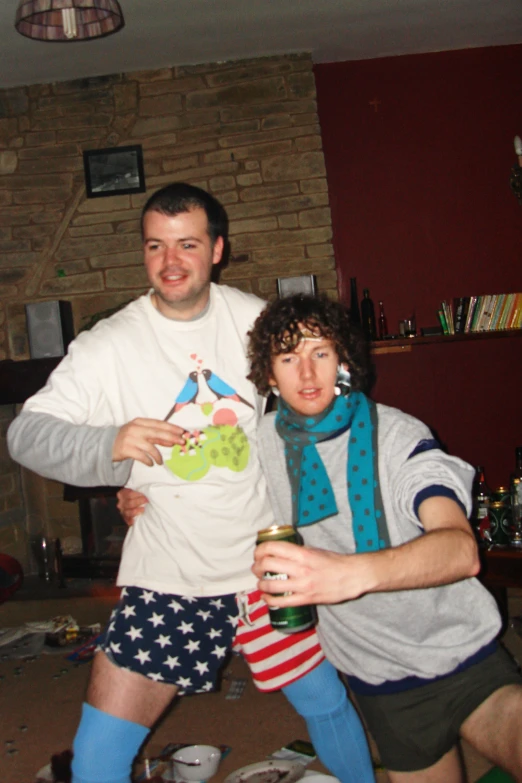 a man in a white shirt holds up a drink as another holds a can