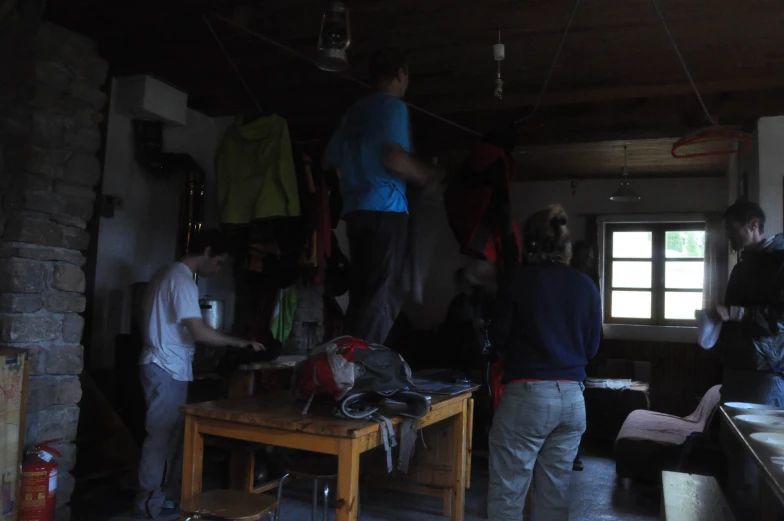 three men are looking through a cluttered kitchen in the evening