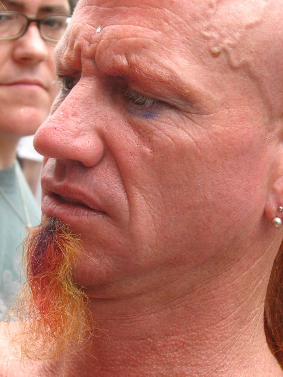 a man with red hair and piercings looking down