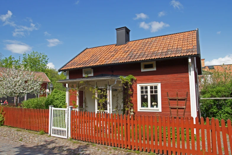 a red house with white pickets near a tree