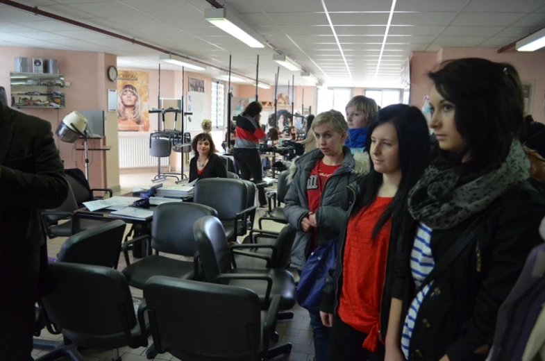 some people sitting on chairs and writing while others stand in a room