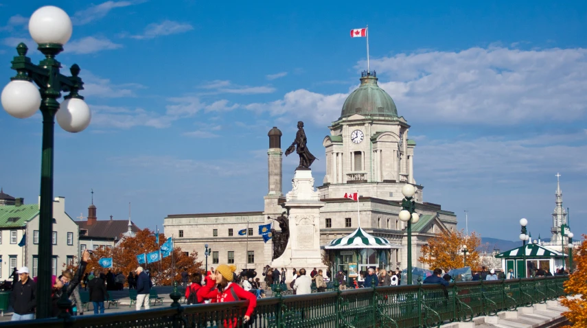 a group of people walk across a bridge in front of a white building