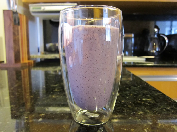 the smoothie is in a clear glass on the counter