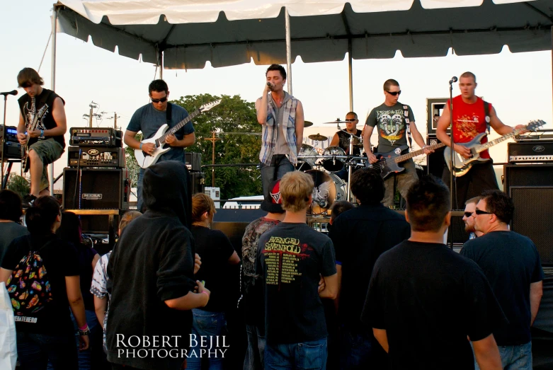 a group of men with guitar and keyboards at an outdoor concert