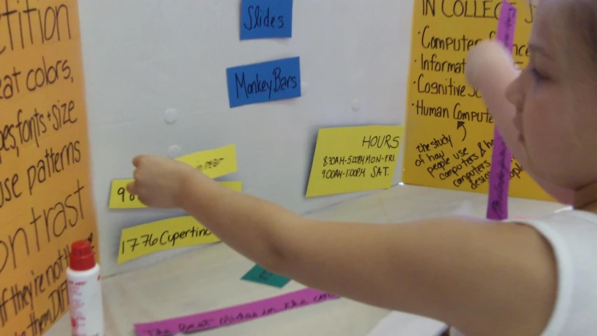 someone pointing to a bulletin with several different colored sticky notes
