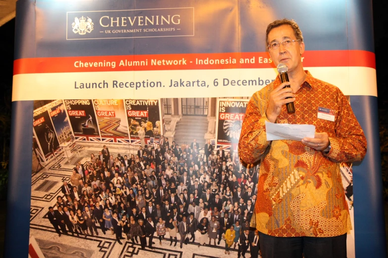 man speaking into microphone in front of a crowd of people