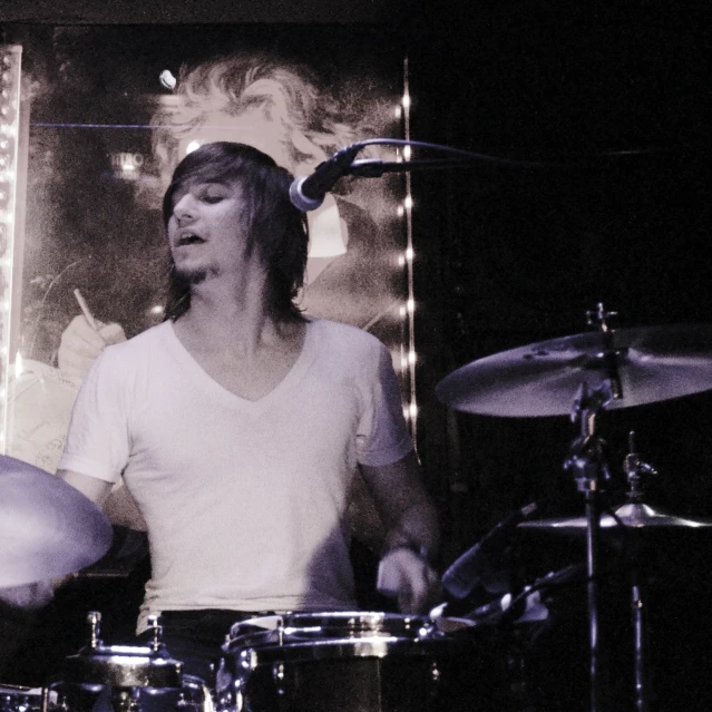 a drummer on stage with headphones on and playing drums