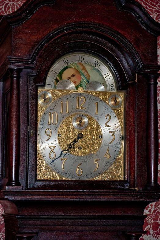 a wooden clock with the face of a baby doll hanging from it