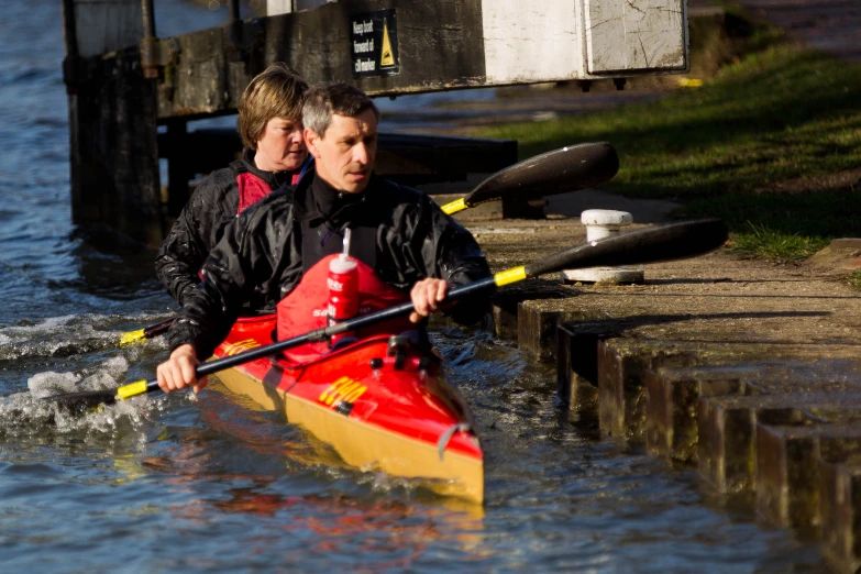 two people are kayaking in the water beside some docks