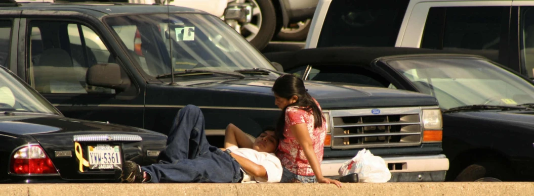 a woman laying on the side of a road next to parked cars