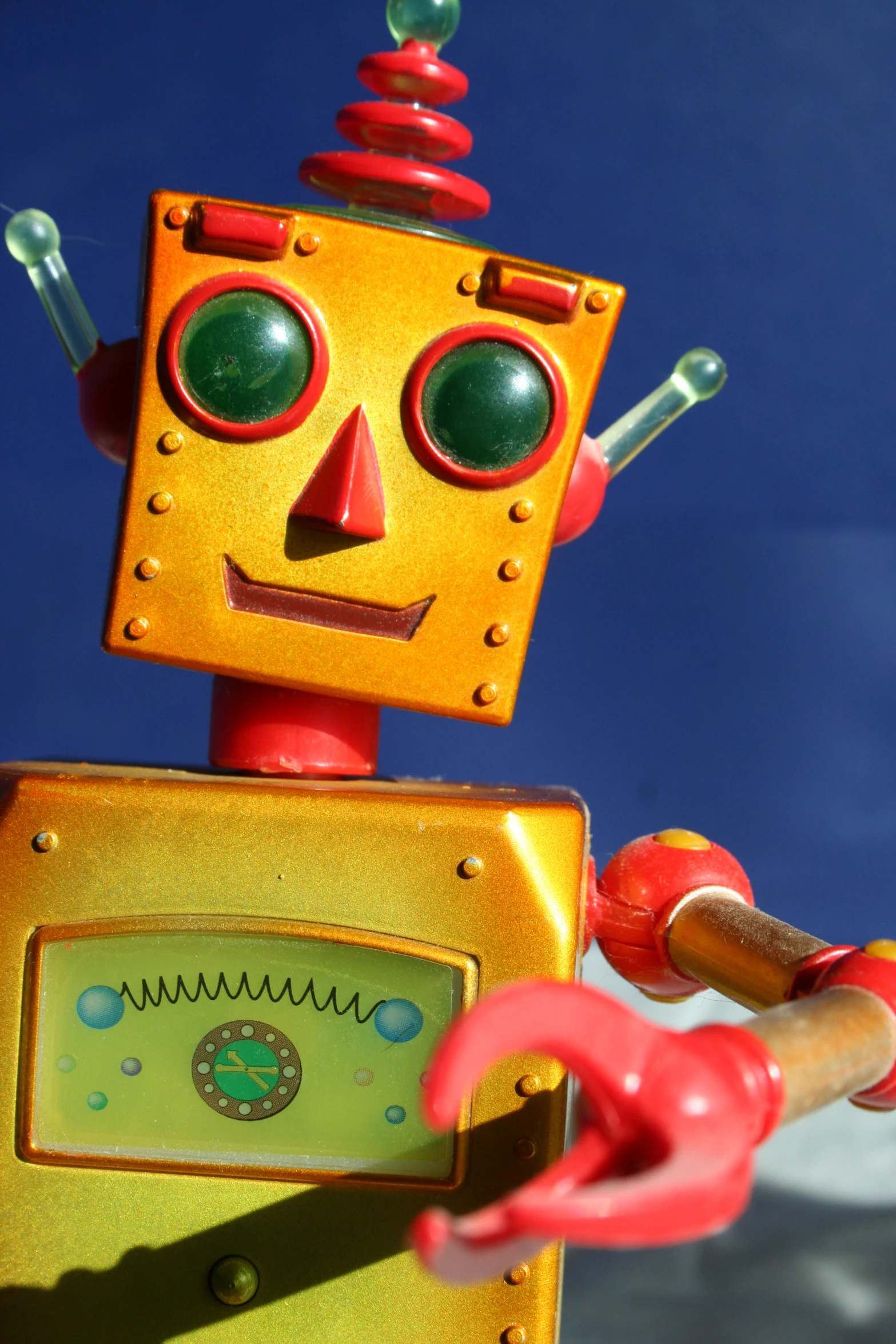 a toy robot with red handles and eyes holds a red object