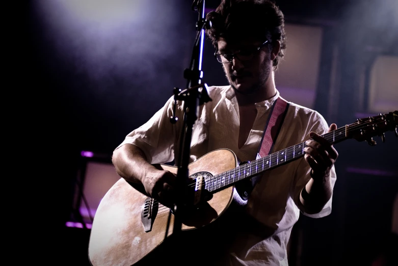 a man playing guitar with a microphone in front of him