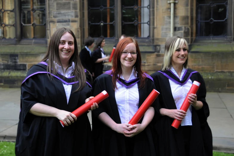 three girls dressed in graduation robes posing together