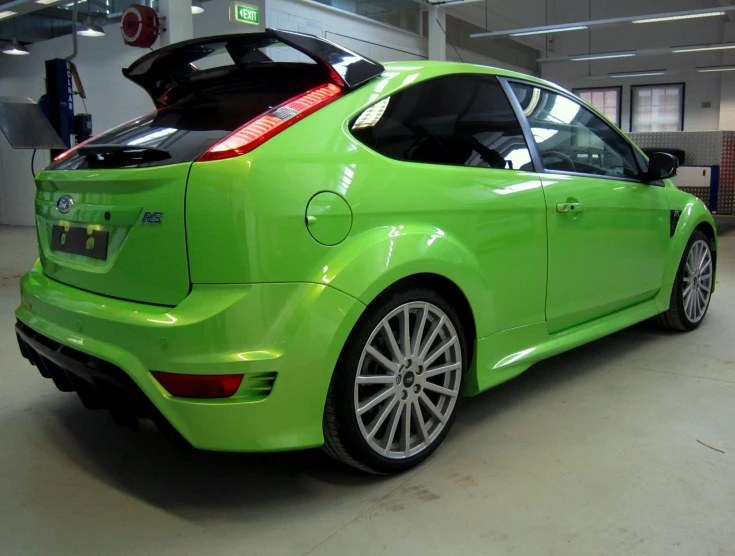 the rear end of a green car parked in a parking garage