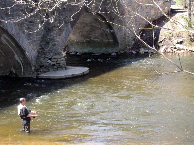 the man is standing by the bridge holding a fish