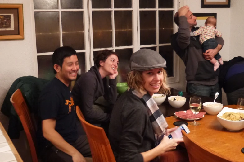 four people sitting around a table holding wine and food