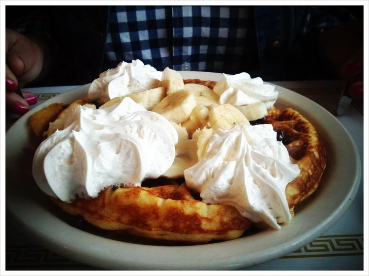 pancakes with whipped cream on top sitting on a plate