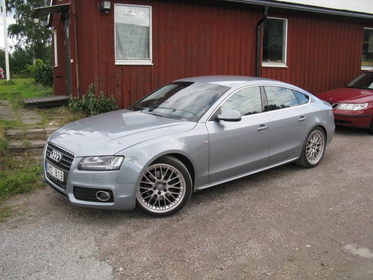 a silver car sitting in front of a red house