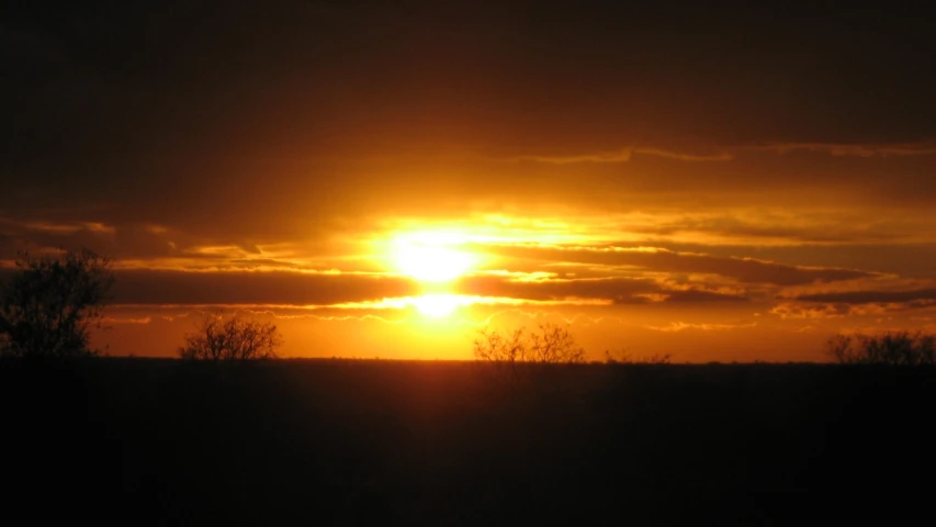 the sun sets over a large field in the middle of nowhere