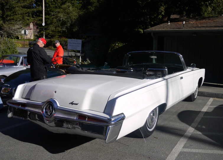people are observing an antique convertible in a car show