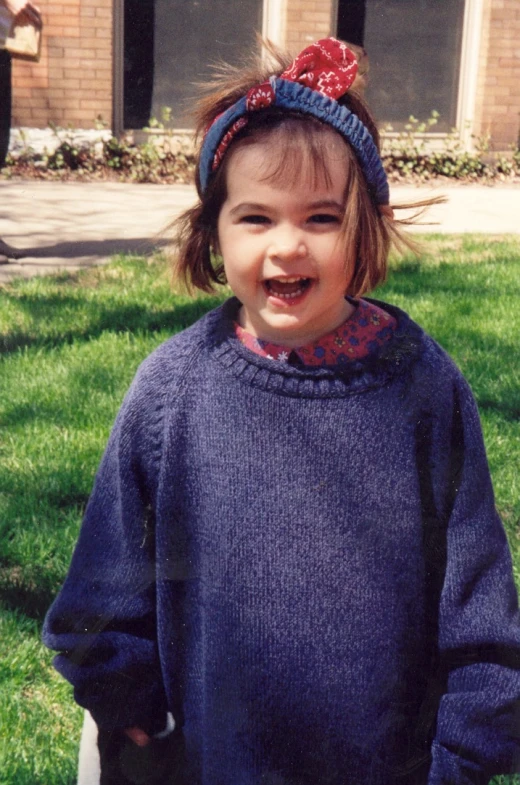 a small child is wearing a blue knitted sweater and smiling