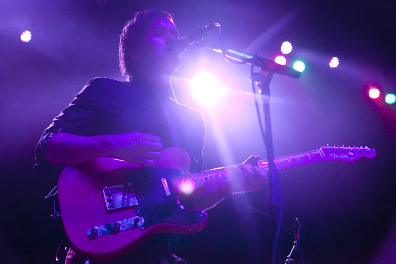 a man holding a guitar up in front of a microphone