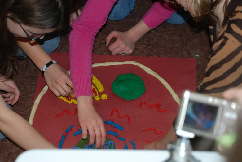 girls are doing art on the floor with a camera