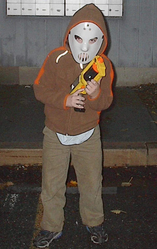 a  wearing a white mask and holding a yellow gun