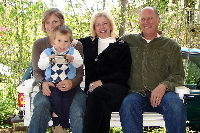 a family poses on a bench in front of trees