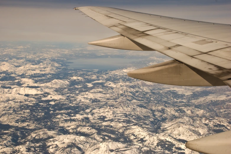 the wing of an airplane is flying above mountains