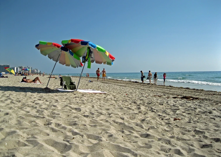 a beach covered in lots of people and a few umbrellas