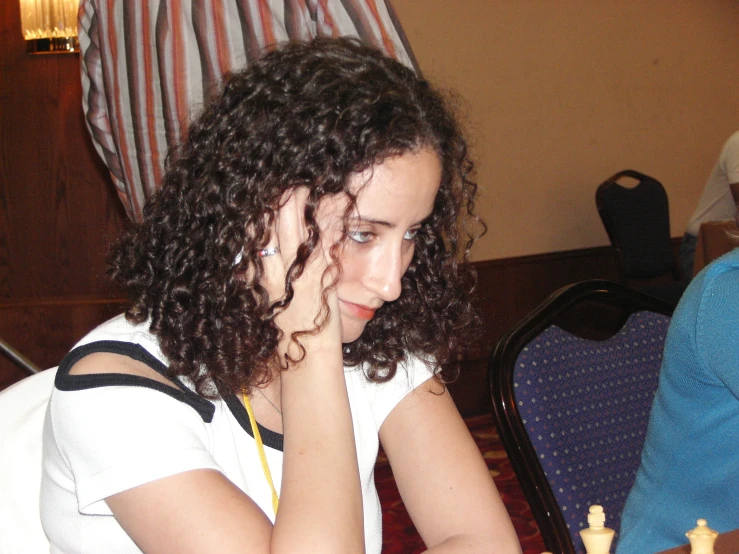 a woman sits at a dining room table with a white plate of food