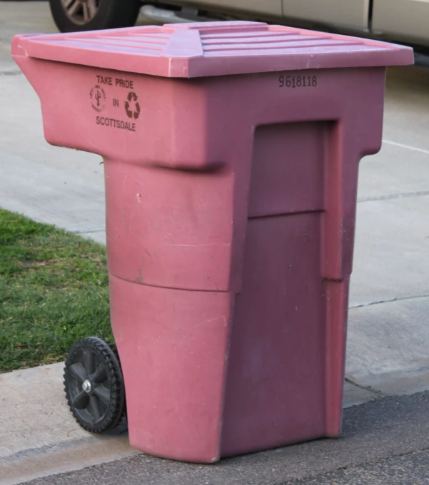 a pink plastic trash can on the side walk