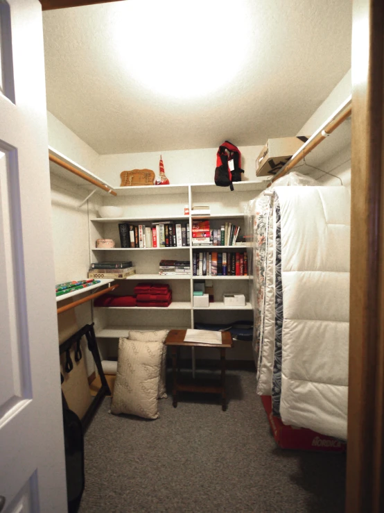 a small bedroom with bookshelf and a table