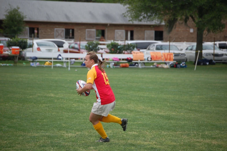 a man wearing a red and yellow uniform is running with a ball