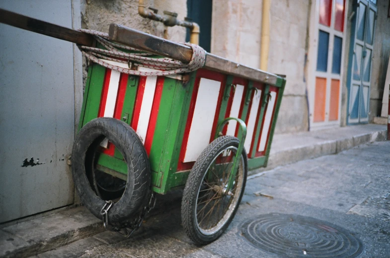 a small red and green cart sitting in front of a building