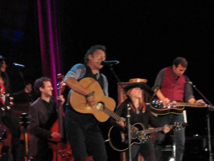 a group of people on stage with guitar and singing